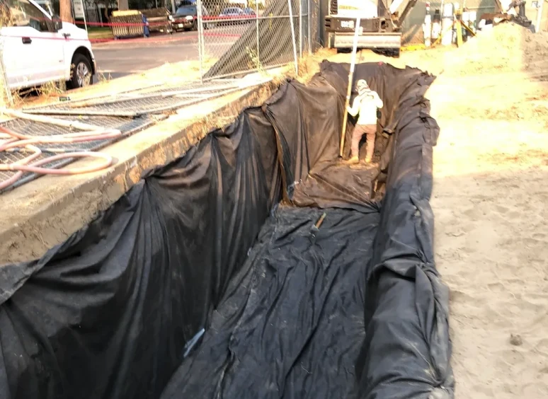 Worker lining a trench with tarpaulin