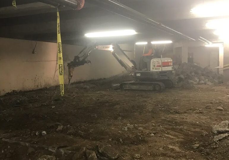 Mini excavator clearing debris indoors